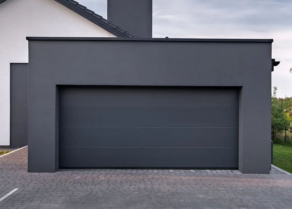 Modernes Einfamilienhaus mit anthrazitfarbenem Sektionaltor und großzügiger Garagenzufahrt.